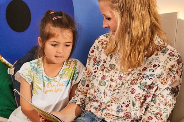 Frau ließt Kind ein Buch vor.